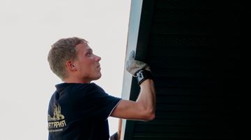 Mand på stige ved hus