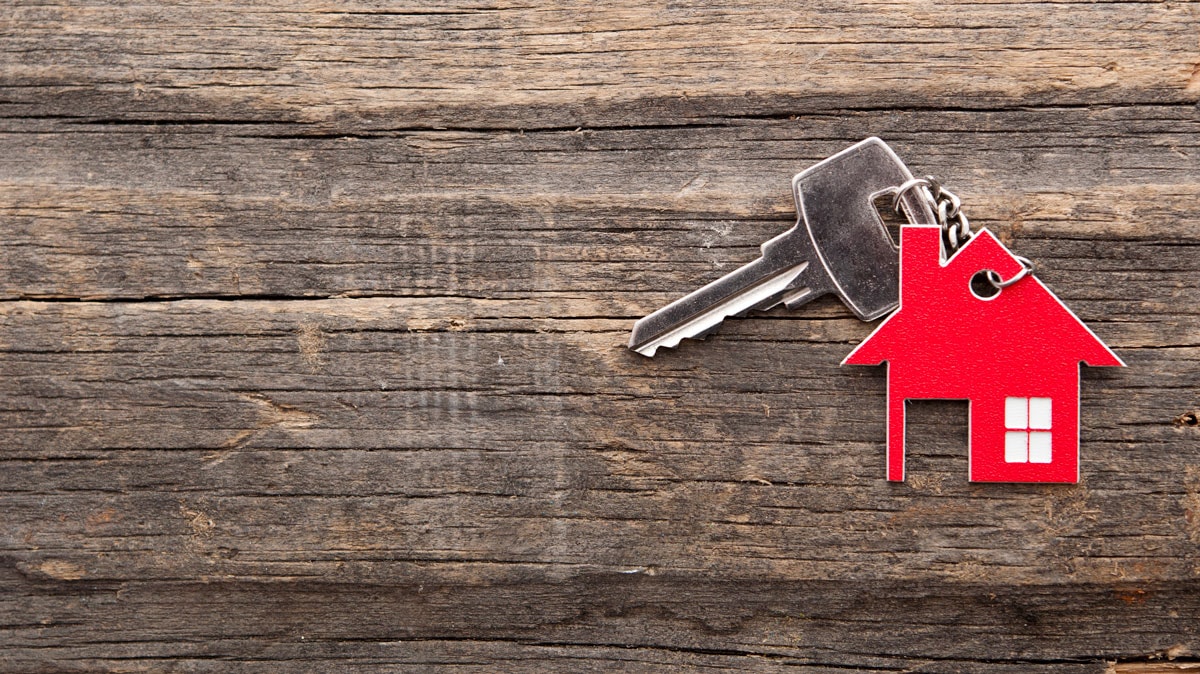 Nøgle med rødt hus som nøglering ligger på træbord
