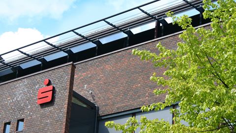 Nærbillede af Sparekassen Thys facade på hovedkontoret i Thisted med bøgetræ foran