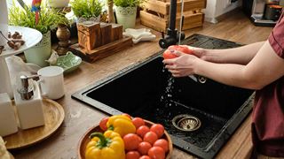 Mand skyller grøntsager i en køkkenvask
